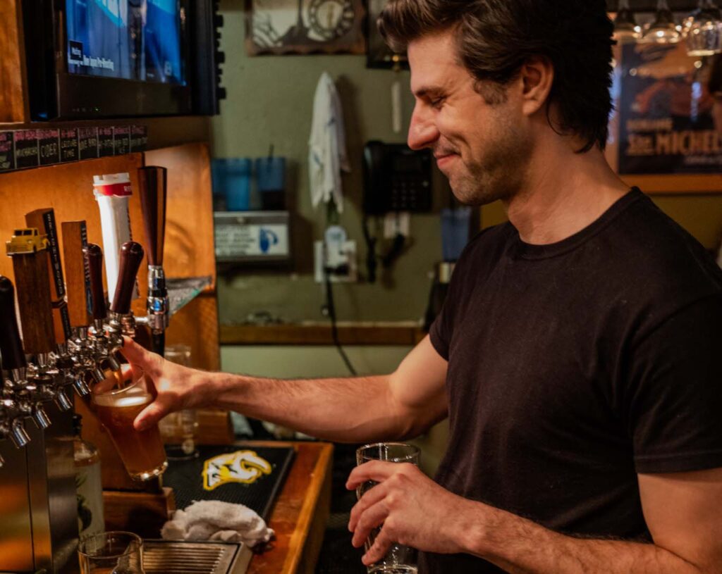 A bartender smiling and pouring a drink